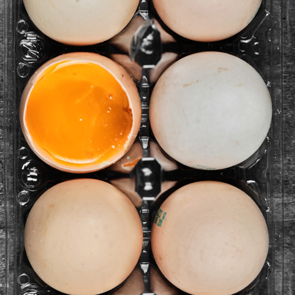 Flat lay closeup view raw and soft boiled eggs on plastic box. High quality photo